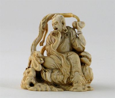 Appraisal: An ivory carving of a figure seated on rockwork holding