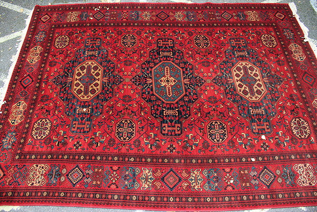 Appraisal: A RED GROUND ORIENTAL CARPET with triple medallion within foliate