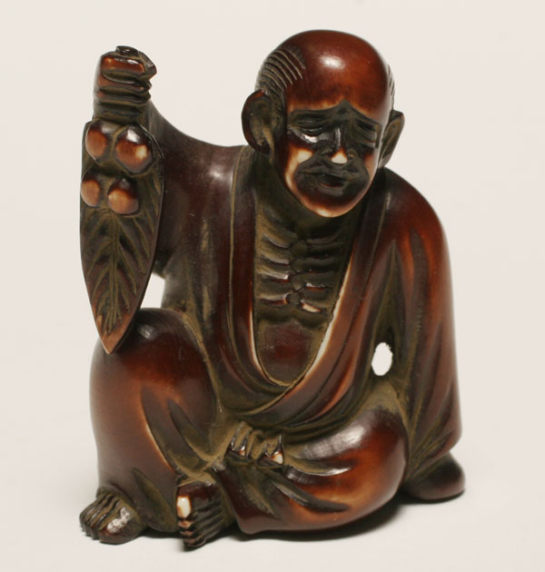 Appraisal: Japanese dyed ivory netsuke seated male figure holding palm Provenance