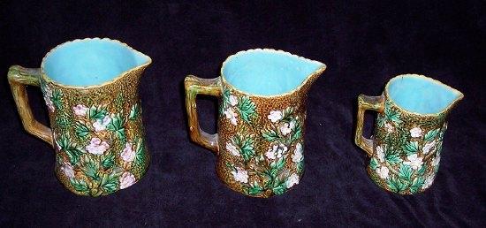 Appraisal: A graduated set of three majolica jugs decorated flowers marked