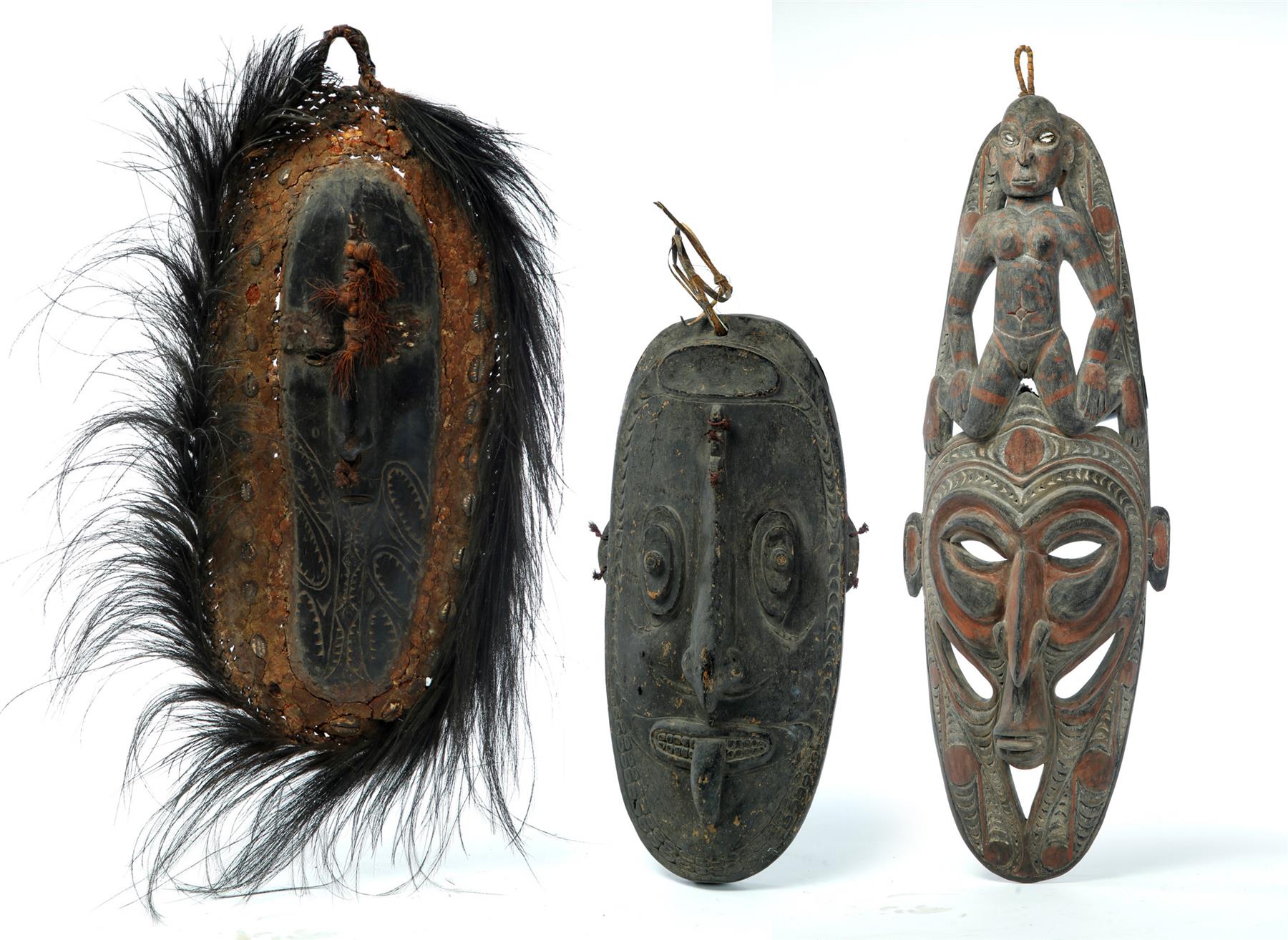 Appraisal: THREE PAPUA NEW GUINEA CARVED MASKS Twentieth century Black stained