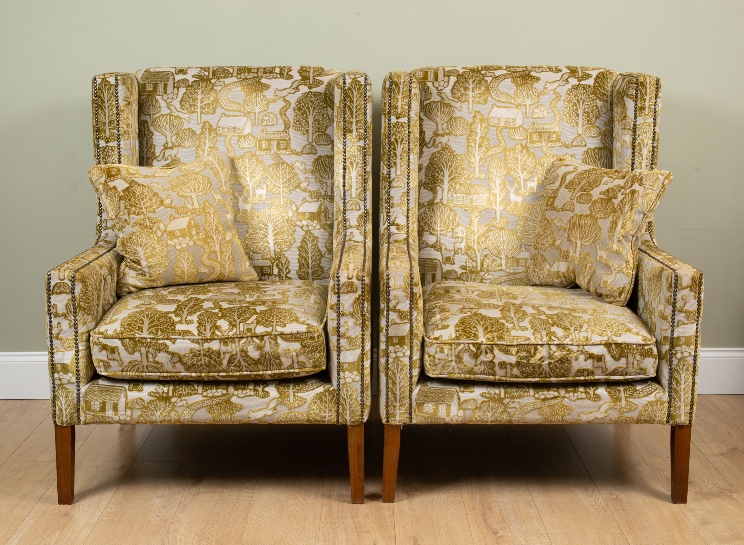 Appraisal: A pair of contemporary wingback armchairs the upholstery decorated with