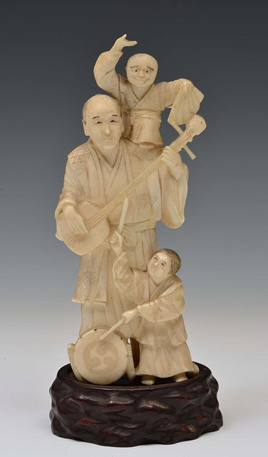 Appraisal: A JAPANESE IVORY OKIMONO standing street entertainer playing a biwa