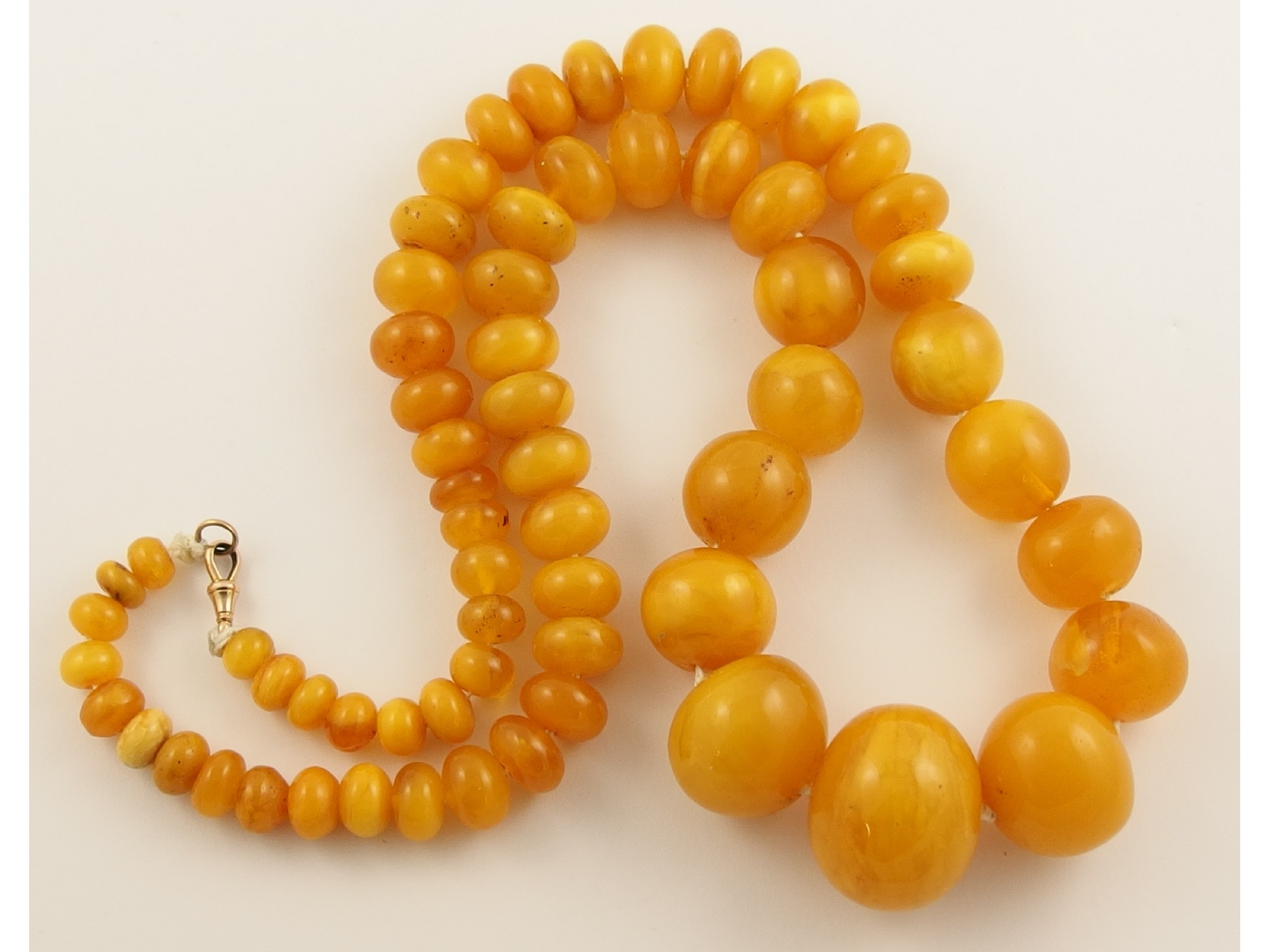 Appraisal: A statement string of yellow amber coloured beadswith swirls of