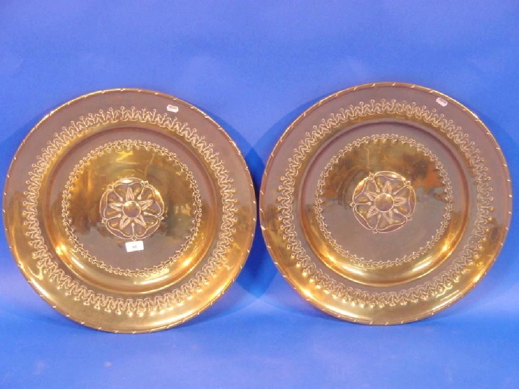 Appraisal: A pair of embossed brass armorial chargers with rose centres