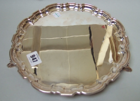 Appraisal: A silver shaped circular salver raised on three scroll and