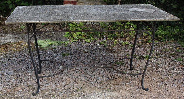 Appraisal: A TRAVERTINE MARBLE TOPPED RECTANGULAR GARDEN TABLE with wrought iron