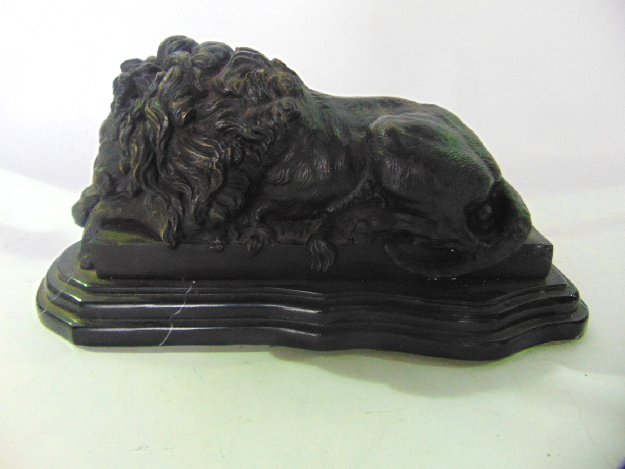 Appraisal: A cast bronze study of a recumbent male lion seated