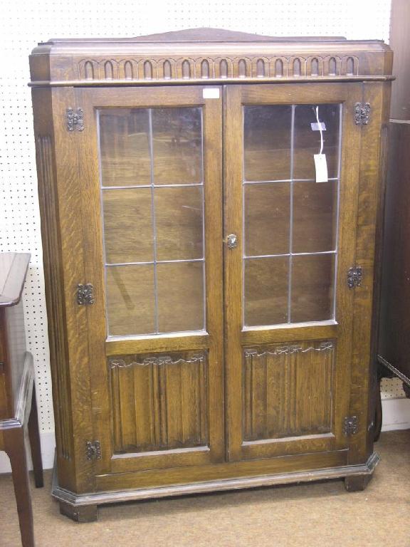 Appraisal: A dark oak veneered display cabinet gouged frieze above a