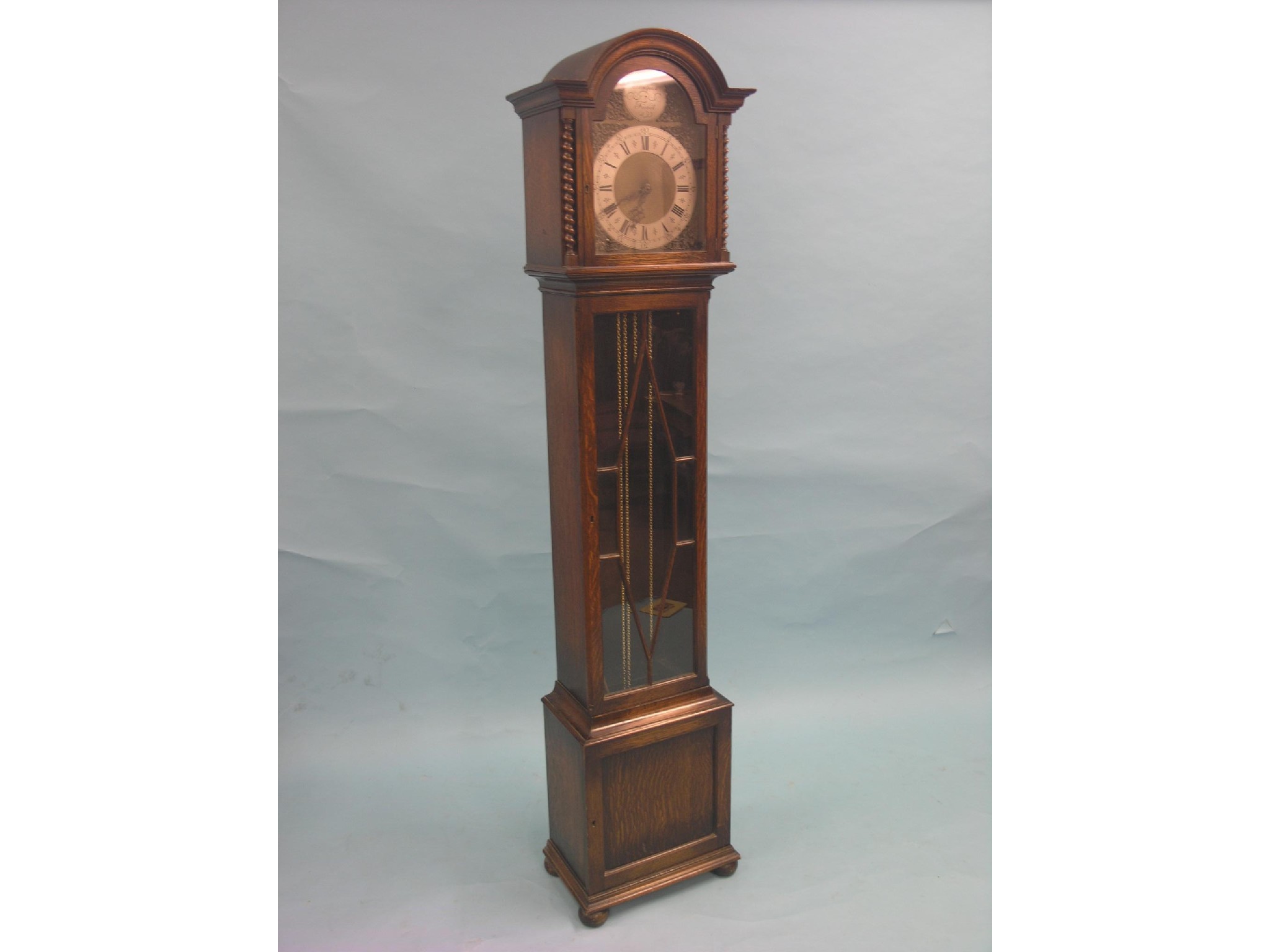 Appraisal: A solid dark oak longcase clock traditional arched brass dial