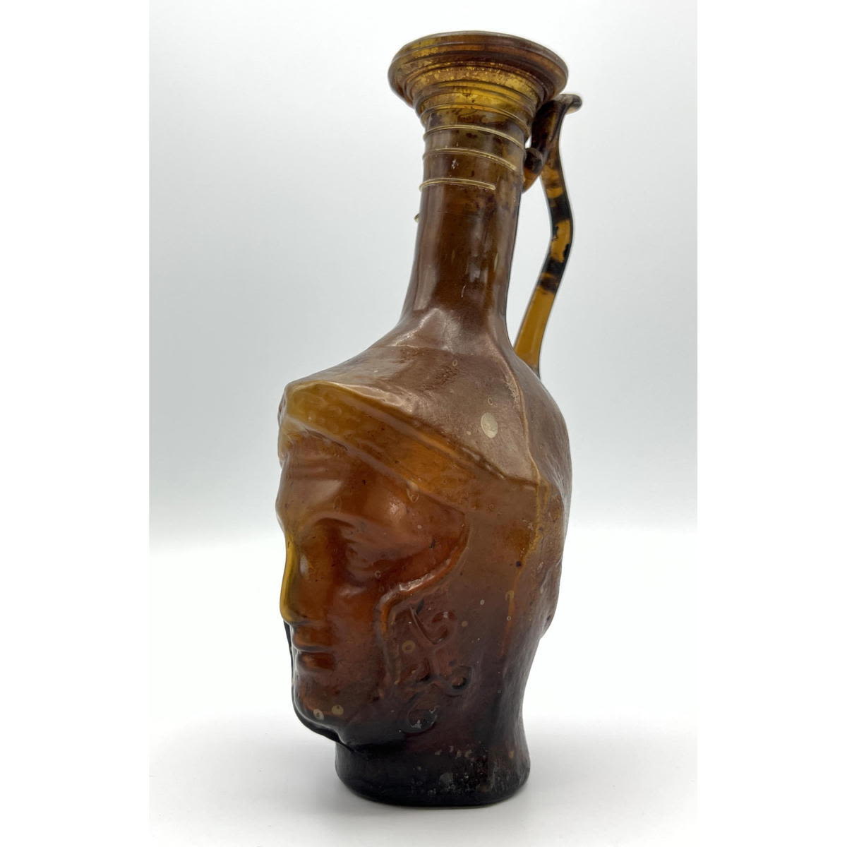 Appraisal: Amber Gladiator face handled jug Ancient Roman glass Dimensions H