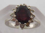 Appraisal: A garnet and diamond cluster ring the central oval stone