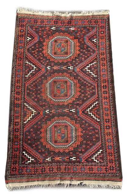 Appraisal: AN OLD BELOUCH WINE GROUND RUG with triple medallion and