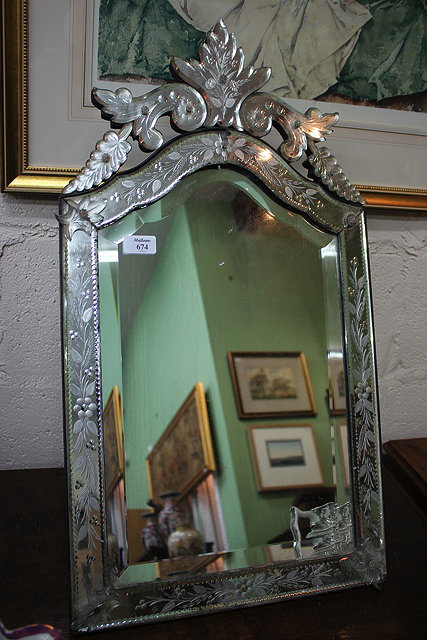 Appraisal: A VENETIAN ETCHED GLASS WALL MIRROR with scrolling foliate crest