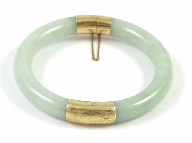 Appraisal: GREEN JADE AND YELLOW GOLD BANGLE The round jade and