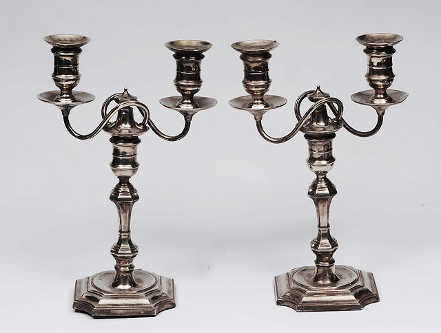 Appraisal: A pair of Georgian style silver candelabrumwith shaped platform bases