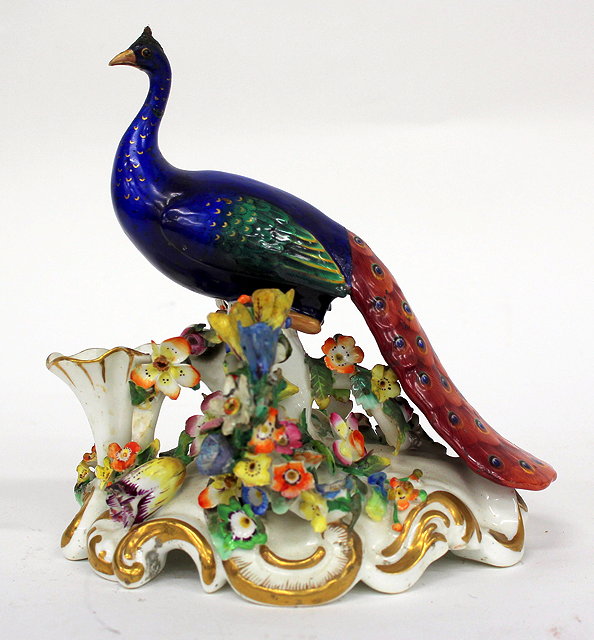 Appraisal: A TH CENTURY ENGLISH PORCELAIN PEACOCK on a flower encrusted