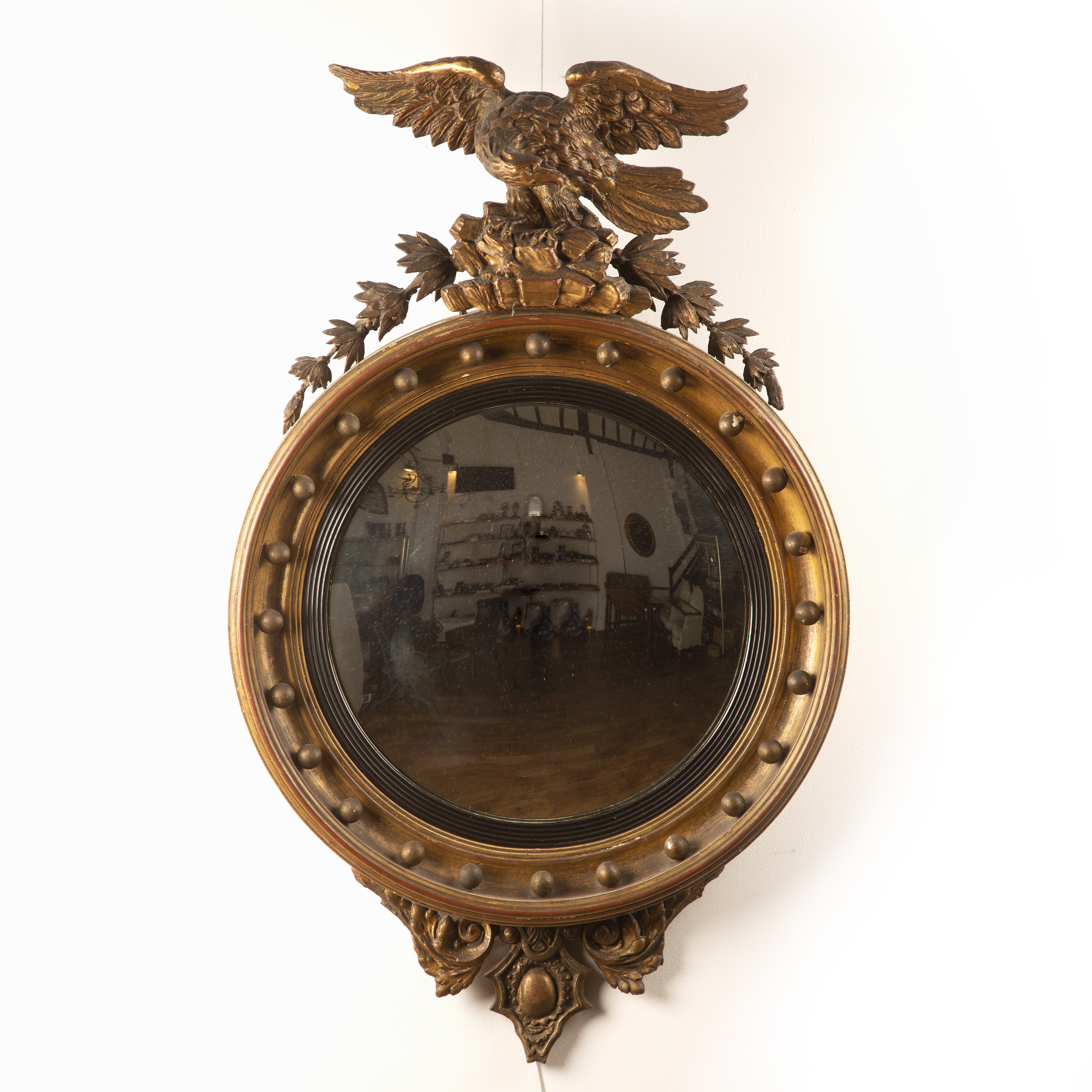 Appraisal: Giltwood convex wall mirrorRegency period with carved eagle mount and