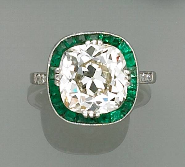 Appraisal: A diamond emerald and platinum ring centering an old cushion-cut