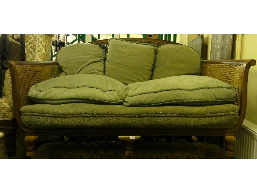 Appraisal: An Edwardian walnut framed bergere sofa with shaped outline and