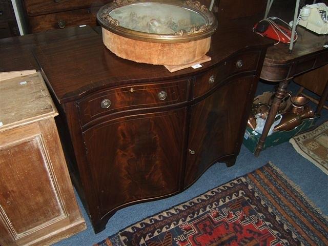 Appraisal: A serpentine fronted mahogany side cabinet with two drawers and