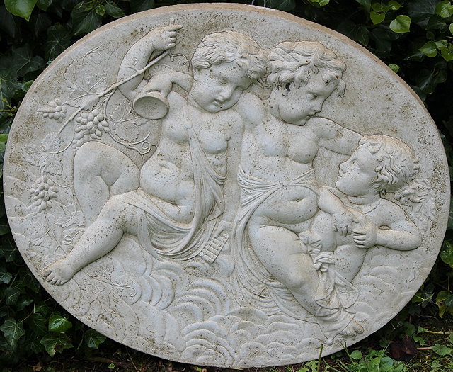 Appraisal: A CAST COMPOSITE OVAL PLAQUE depicting three cavorting putti cm