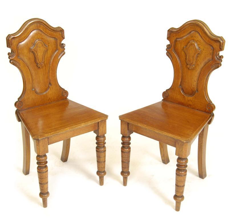 Appraisal: A pair of late Victorian oak hall chairs