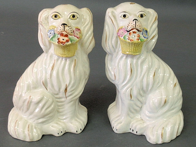 Appraisal: Pair of Staffordshire white seated spaniels holding baskets of flowers