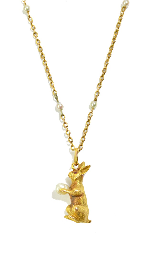 Appraisal: A gold pendant designed as a seated rabbit clutching a