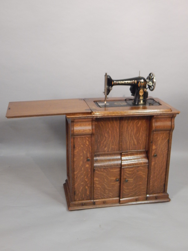 Appraisal: A Singer sewing machine housed in an oak cabinet with