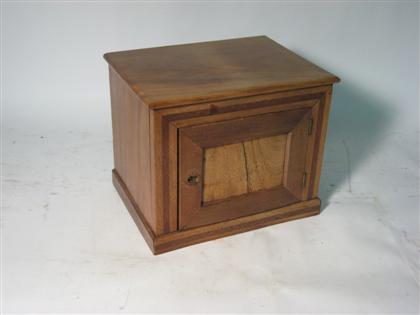 Appraisal: A walnut and mahogany single door cabinetWith a rectangular plain