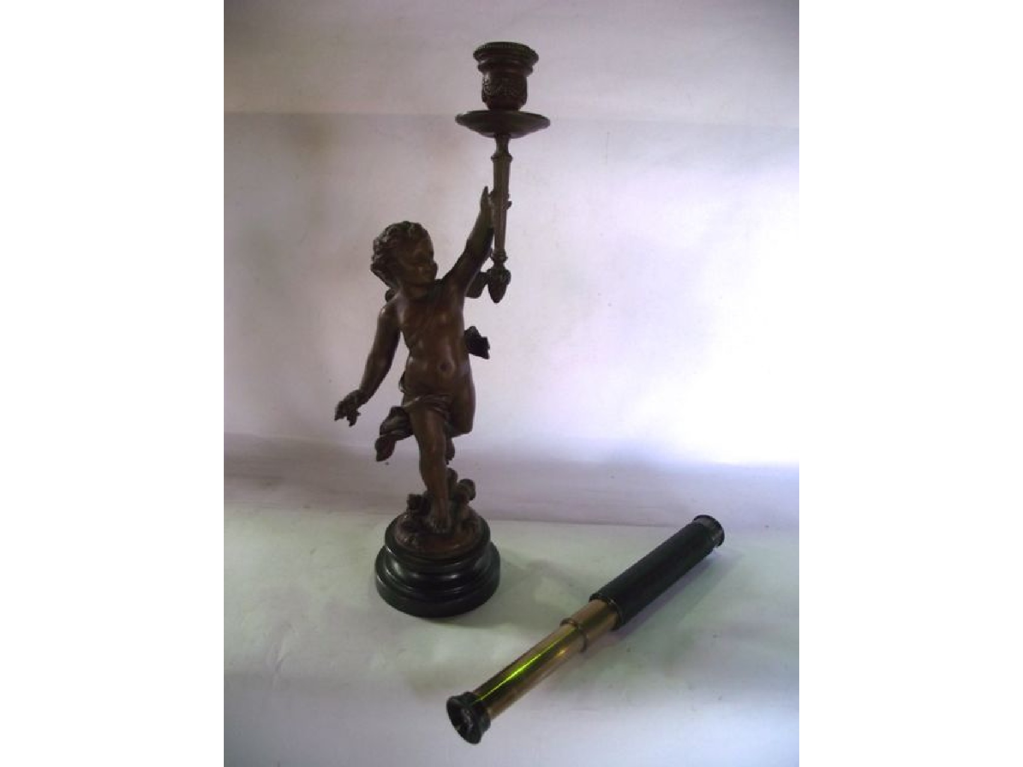 Appraisal: A small pocket telescope and a spelter candlestick with figure