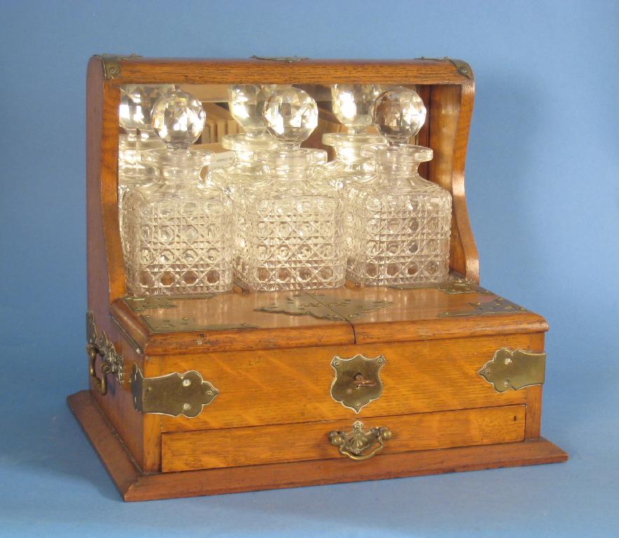 Appraisal: An Edwardian brass mounted oak Tantalus fitted three square cut