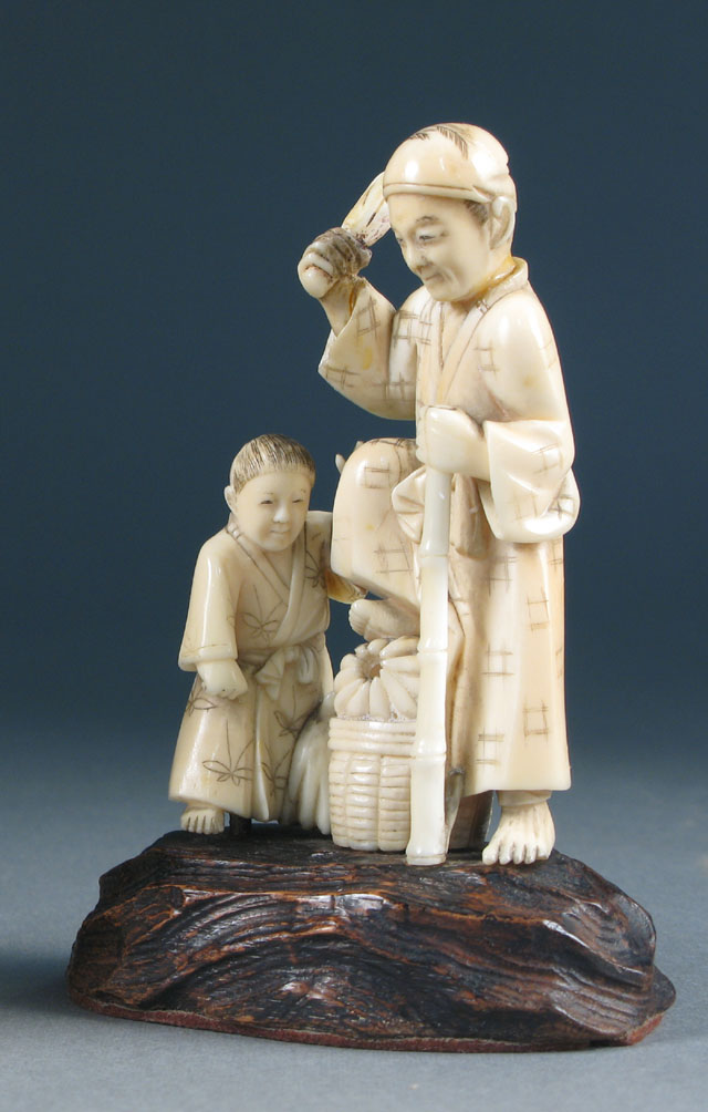 Appraisal: JAPANESE IVORY CARVED FIGURES man holding bamboo staff foot on