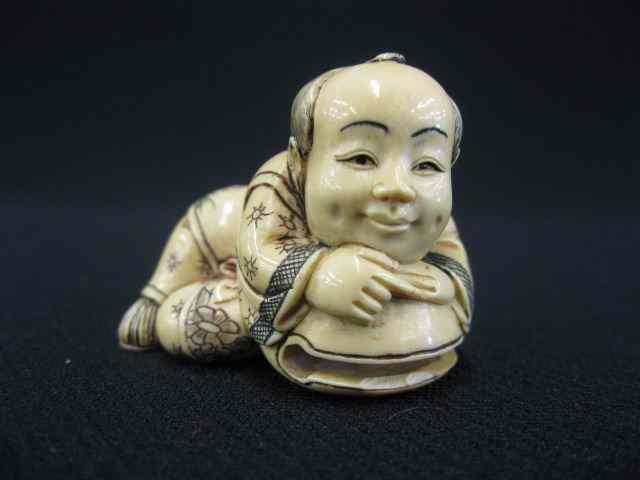 Appraisal: Carved Ivory Netsuke of a Child reclining fancy polychrome signed