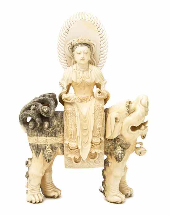 Appraisal: A Carved Ivory Figure of a Deity depicted seated atop