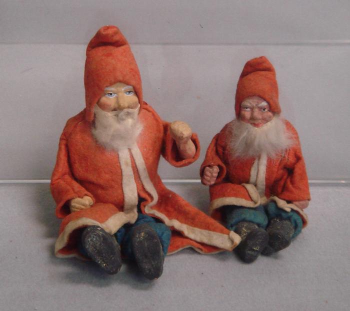 Appraisal: seated paper mache jointed Santa figurines red felt jackets and