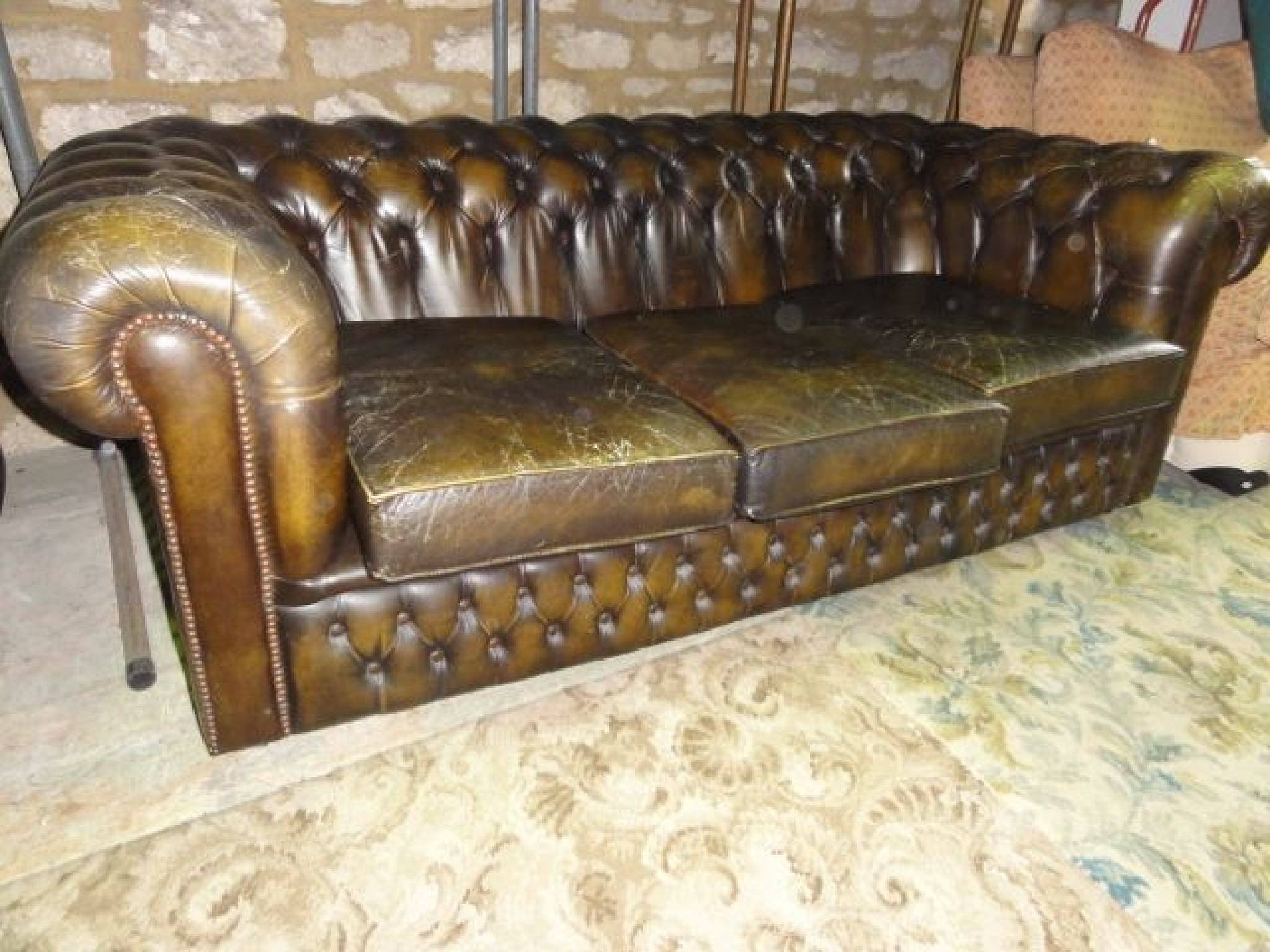 Appraisal: A contemporary worn -seat Chesterfield type sofa with buttoned upholstery