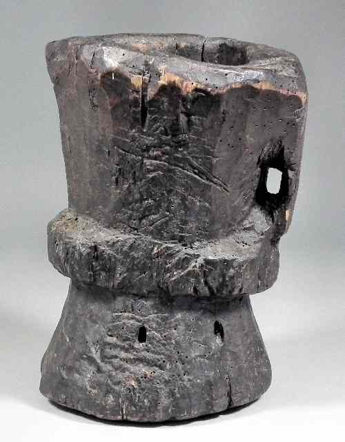 Appraisal: An ancient wooden mortar of waisted form with loop handle