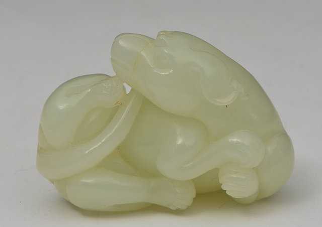 Appraisal: A CHINESE WHITE JADE PEBBLE carved as a recumbent dog