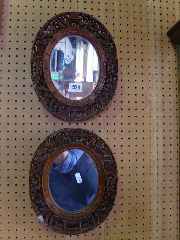 Appraisal: A pair of small oval carved Chinese hardwood wall mirrors