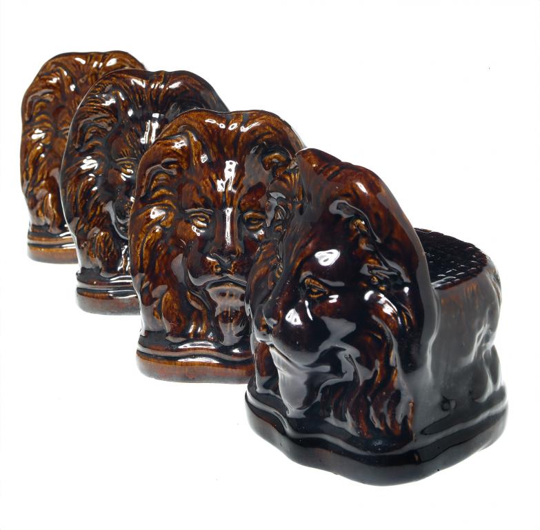 Appraisal: A SET OF FOUR BROWN GLAZED STONEWARE MOULDED LION WINDOW