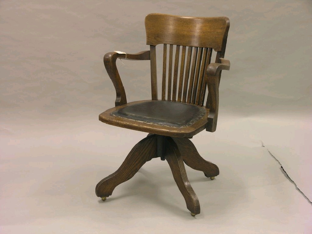 Appraisal: An Edwardian oak desk chair with slatted back upholstered seat