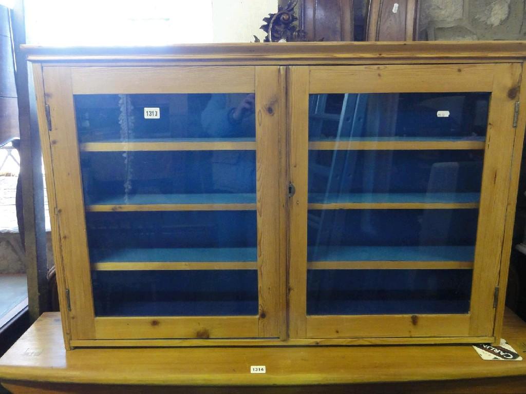 Appraisal: A stripped and waxed pine wall mounted display cabinet enclosed