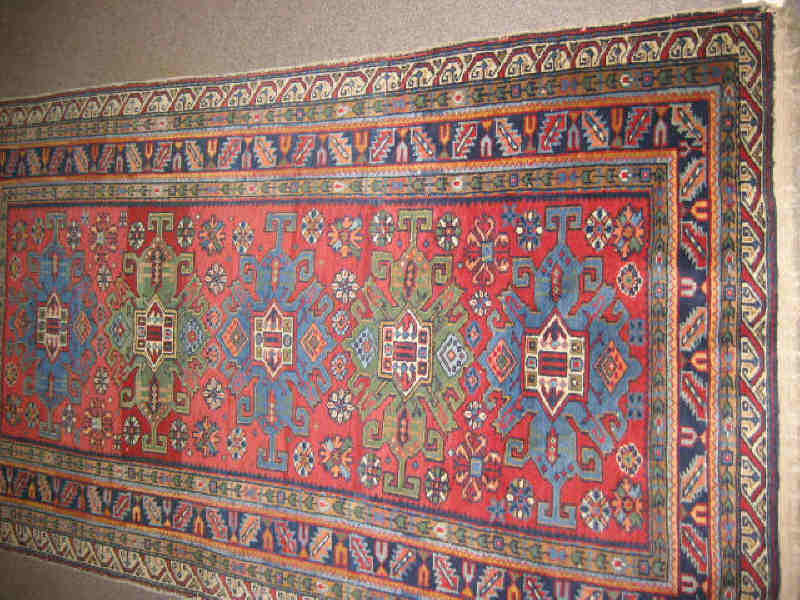 Appraisal: CAUCASIAN THROW RUG The red field of geometric motifs centers