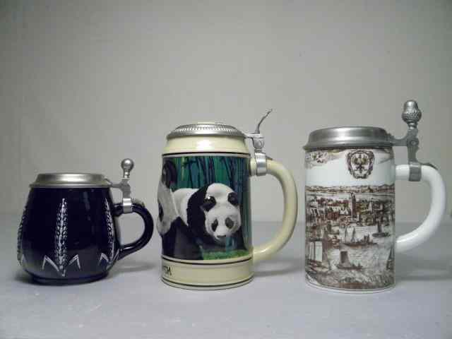 Appraisal: Three porcelain pewter beer steins Includes a deep cobalt blue