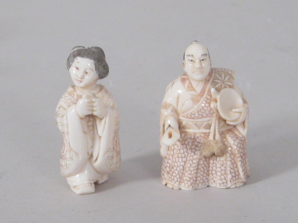 Appraisal: Two Japanese ivory Netsuke lady and gent engraved and coloured