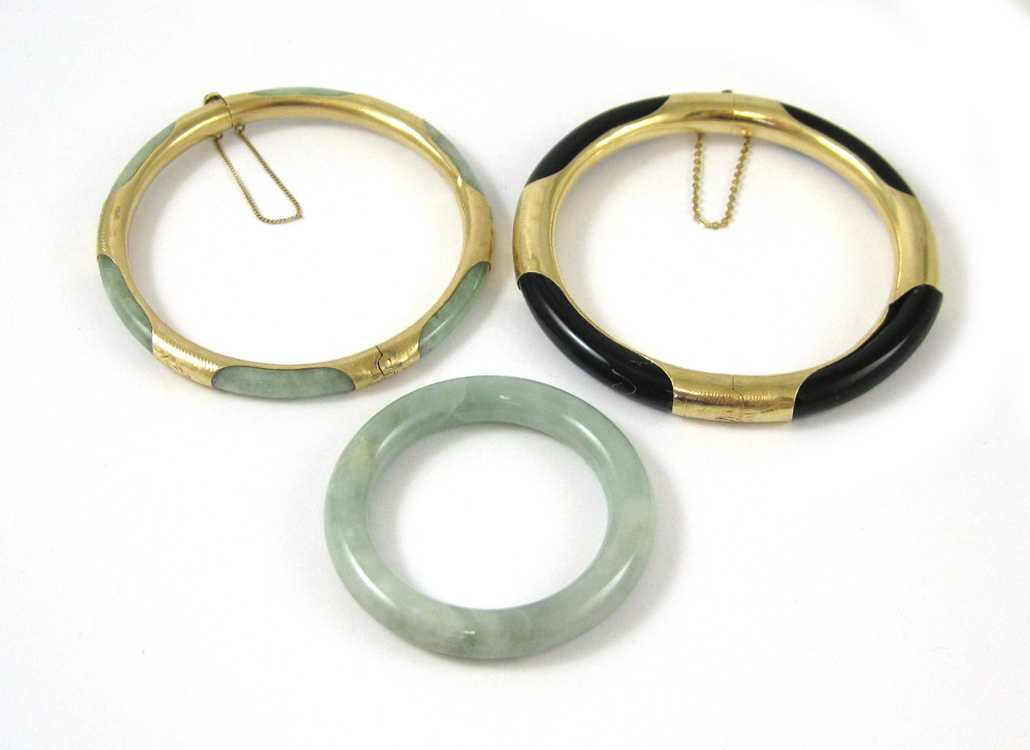 Appraisal: THREE CHINESE HARDSTONE BANGLES black coral and K yellow gold