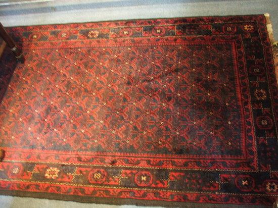 Appraisal: A BELOUCH WINE GROUND RUG decorated central continuing stylised pattern