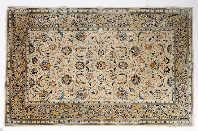 Appraisal: A KASHAN CREAM GROUND RUG with a simple scrolling foliage